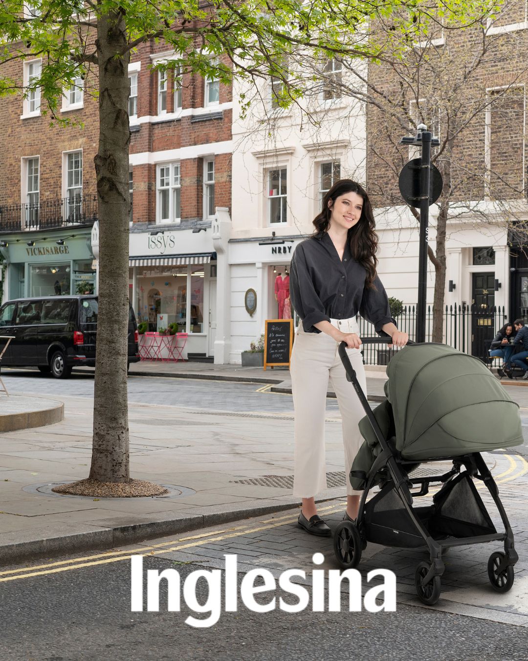 mama paseando por la ciudad con un carrito de bebé Inglesina color verde 